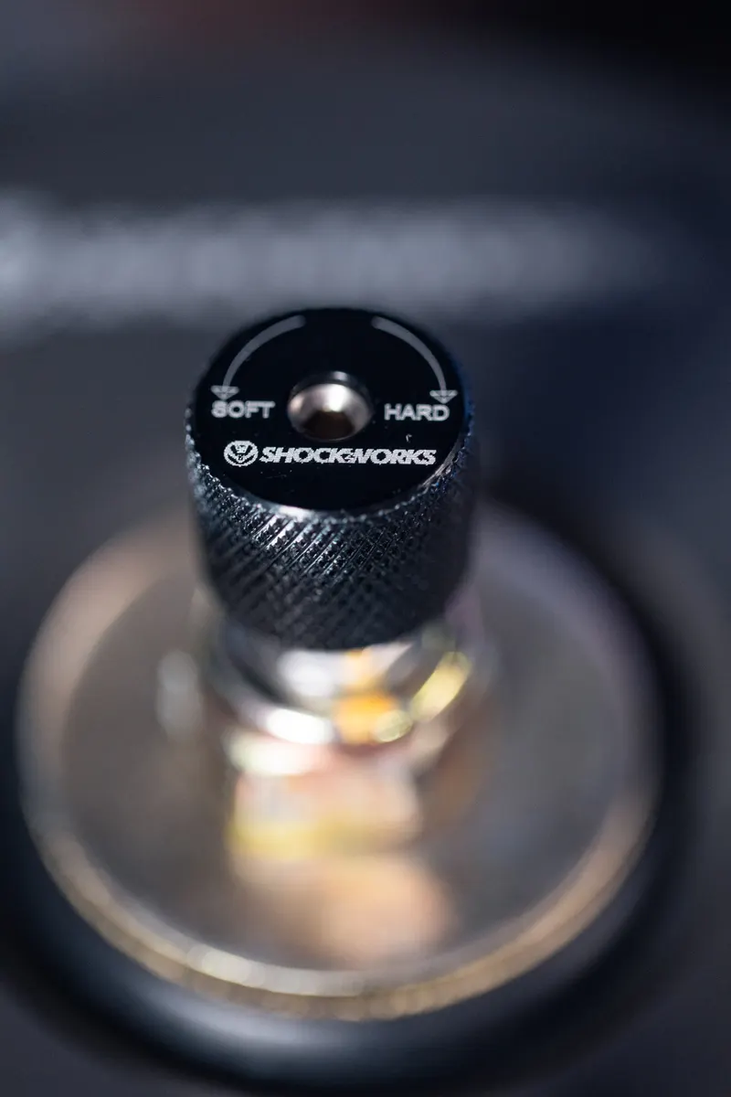 The knurled damping adjuster on top of a Shockworks coilover, marked soft and hard