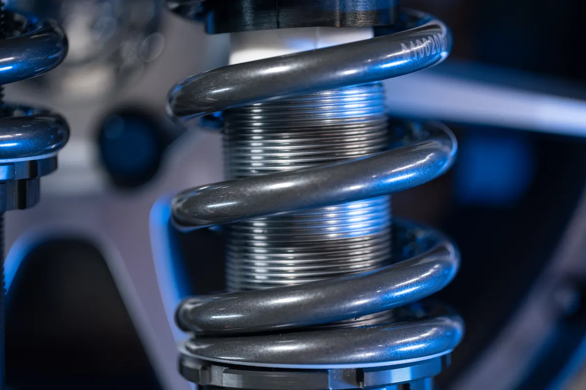 A coil spring wound around the threaded body of a Shockworks damper, up close