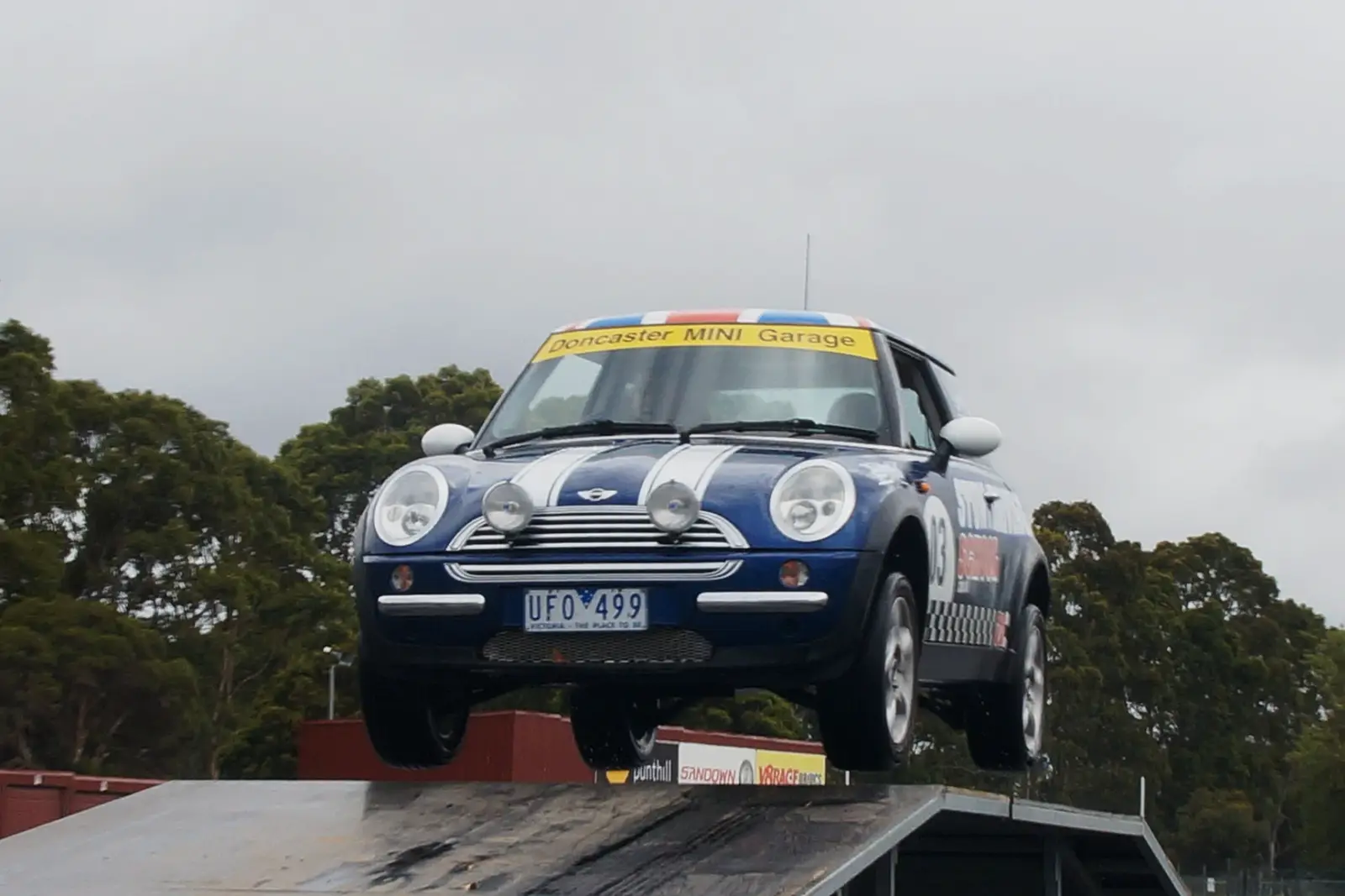 The Doncaster MINI Garage rally Mini airborne off a ramp, all four wheels clear of the deck
