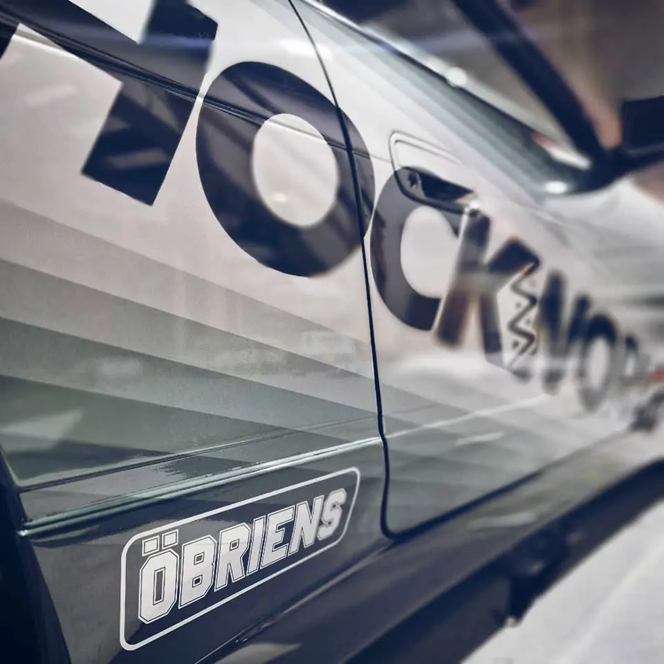 SHOCKWORKS lettering along a ute's flank in monochrome, with an Ă–BRIENS sticker on the sill