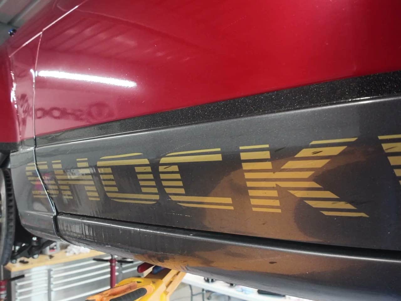 The Shockworks name being stencilled along the S13 sill in gold, car on the hoist